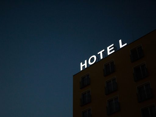 low-angle photo of Hotel lighted signage on top of brown building during nighttime