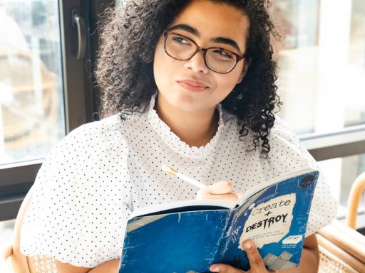 woman in white and black polka dot shirt holding blue and white book